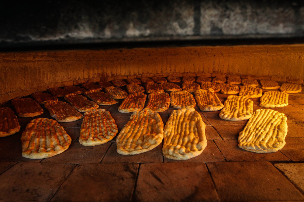 Baker stretching barbari dough and pressing grooves along its length