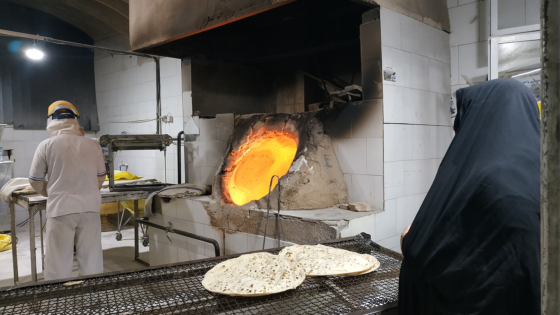 Customers buying fresh flatbread at an Iranian bakery counter